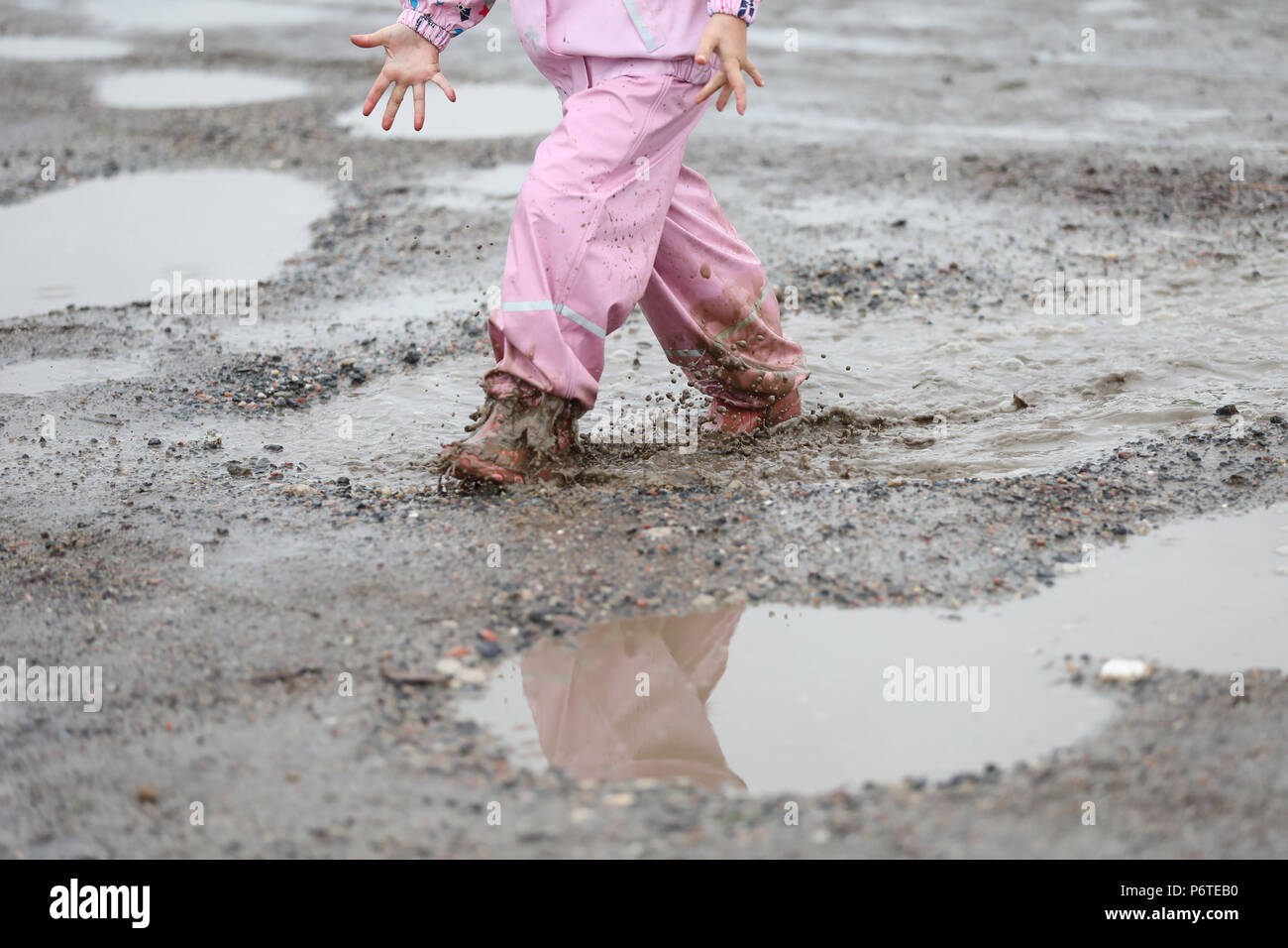 Hamburg, close-up, child in rain gear running through a puddle Stock Photo