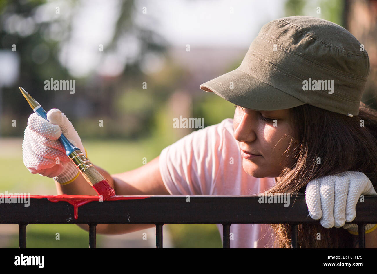 Pretty girl is painting metal fence with a brush Stock Photo Alamy