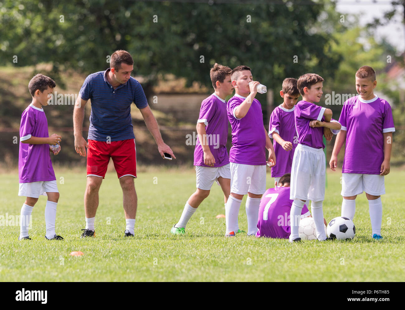 Coach is giving advice to young soccer players at football match Stock