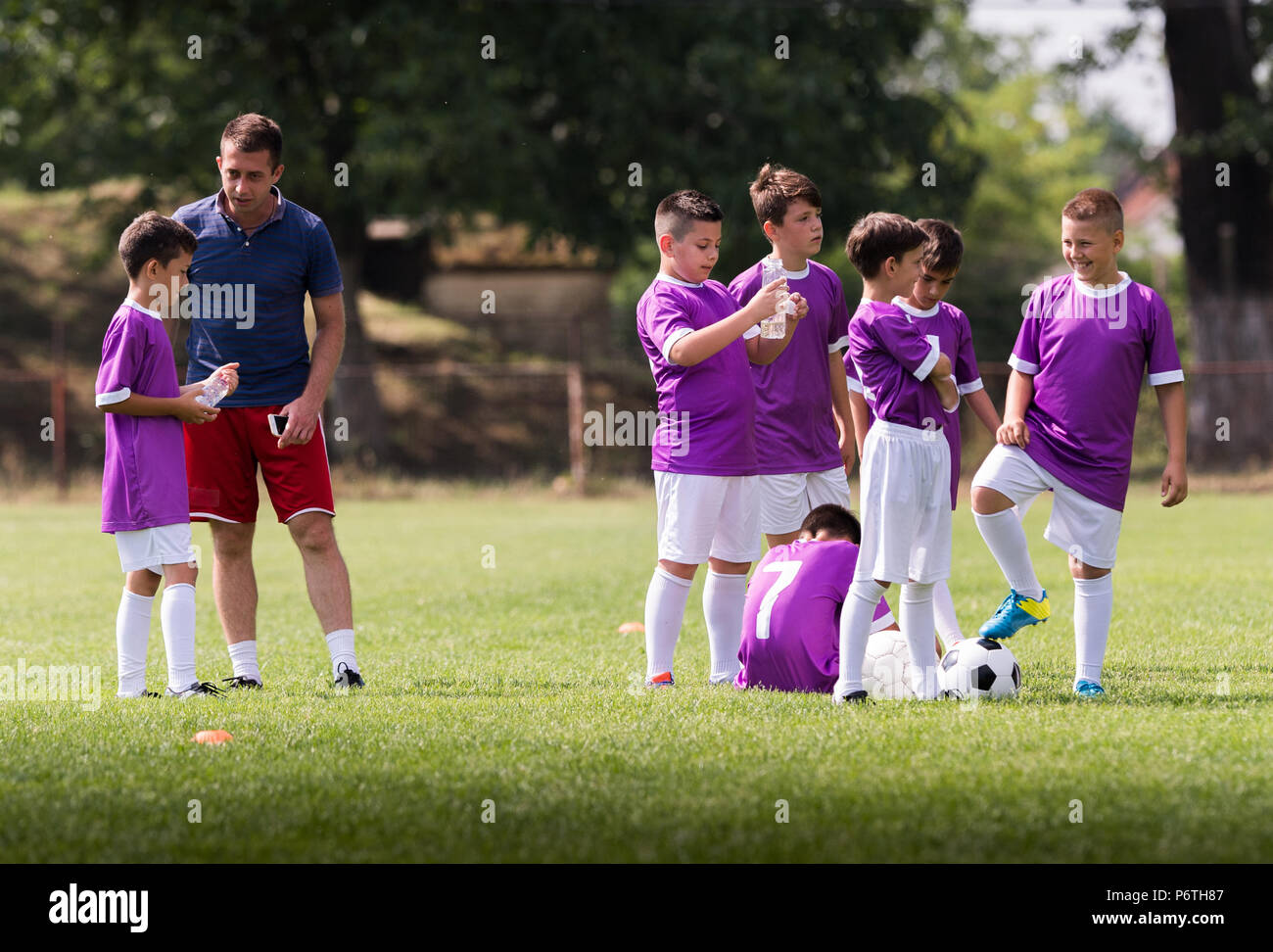 Coach is giving advice to young soccer players on football match Stock