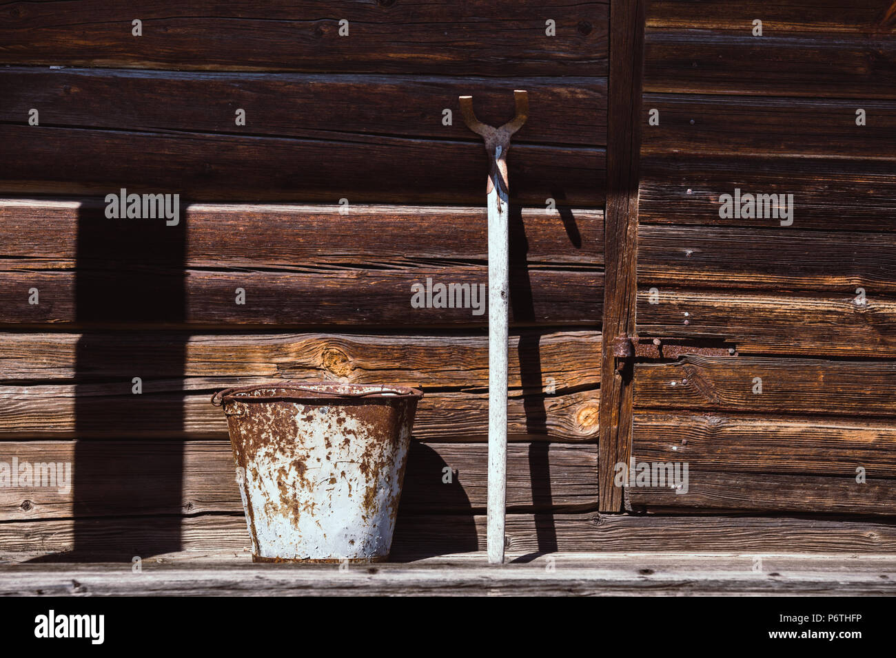 Old rusty metal bucket and mattock against weathered girder wall Stock Photo