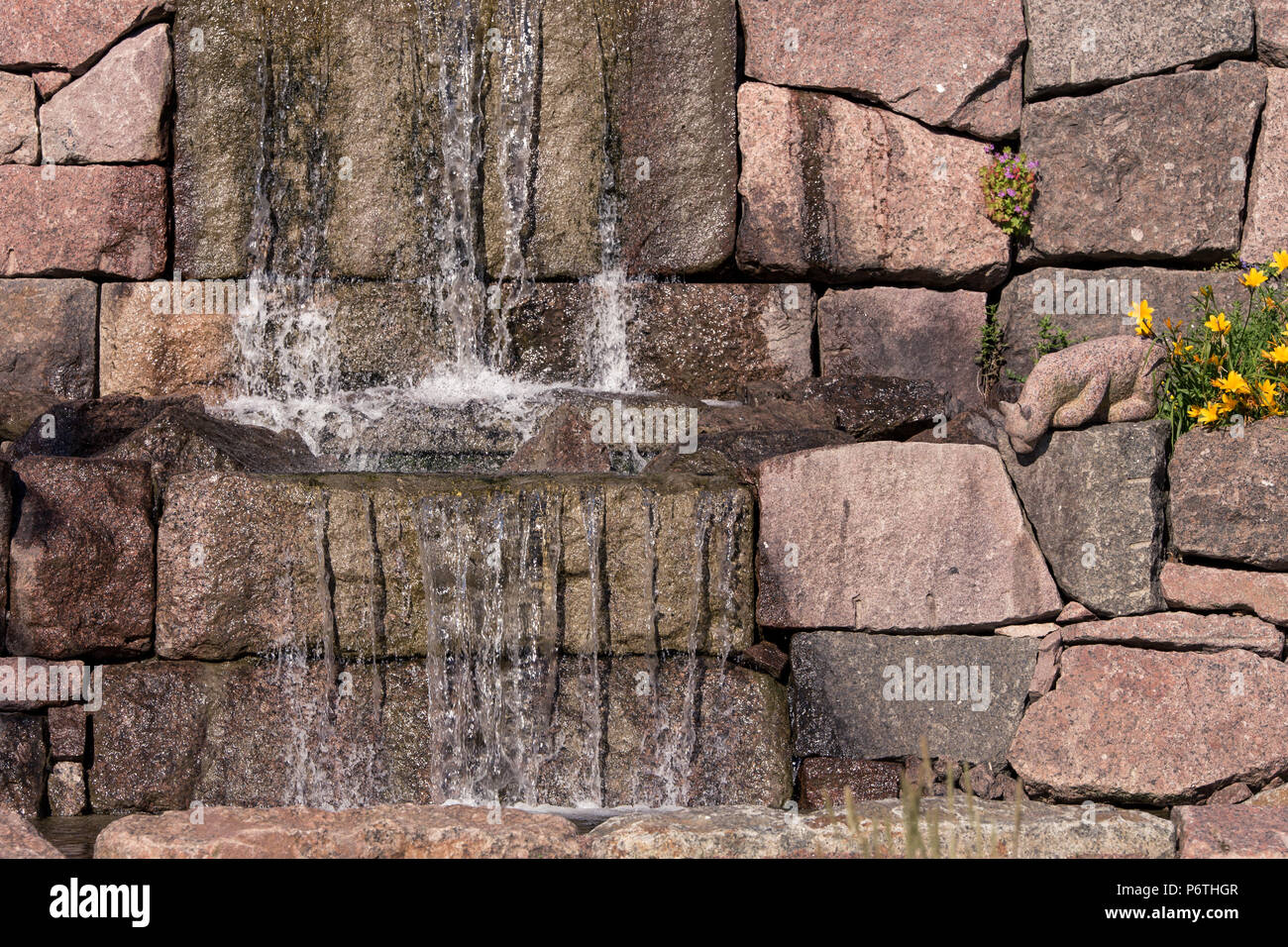Waterfall with granite rocks and cat statue in Jokipuisto, Kotka, Finland Stock Photo