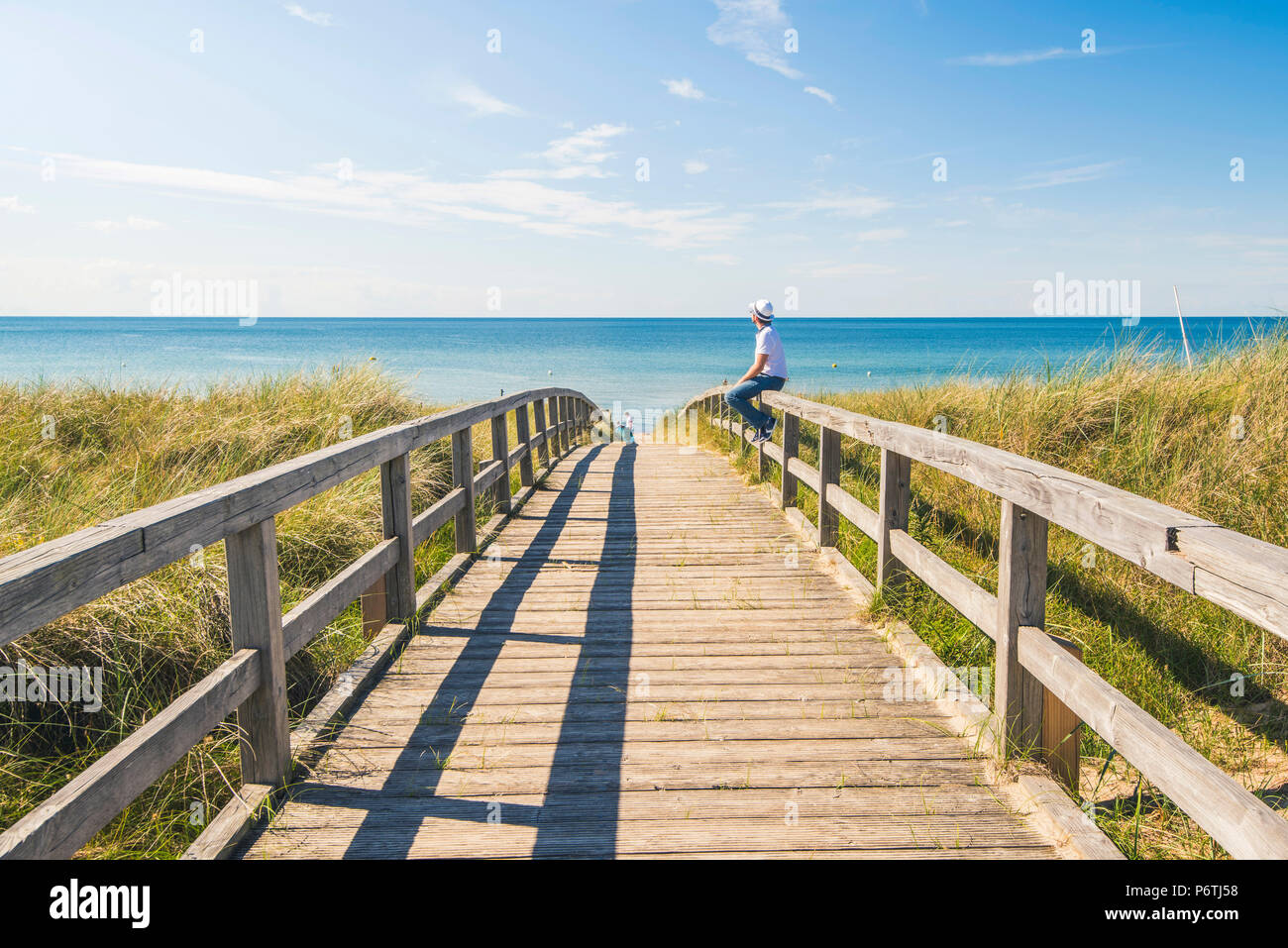 Man standing on a footbridge to WeissenhÃ¤user Strand, Ostholstein, Schleswig-Holstein, Germany (MR). Stock Photo