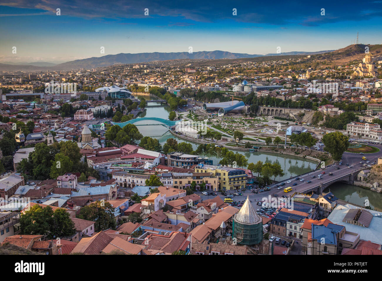 Georgia, Tbilisi, View of Tbilisi looking towards Metekhi bridge, Peace bridge and the Public Service Building, on the right - Rike Park Theater and Exhibition Hall below the Presidential Palace and Tsminda Sameba Cathedral (Holy Trinity Cathedral) Stock Photo