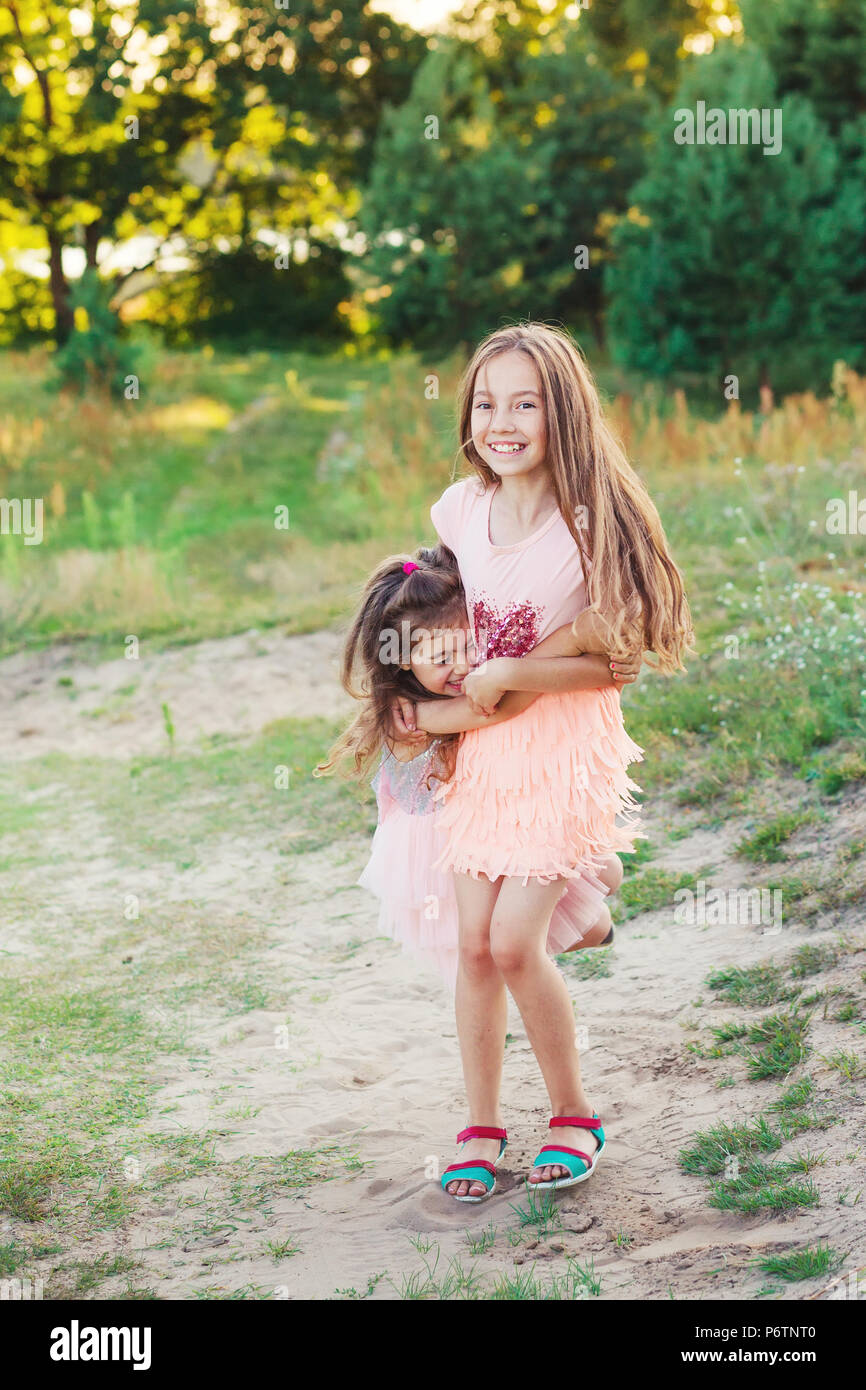 Two Happy little girls having fun and embracing  at sunny summer day Stock Photo