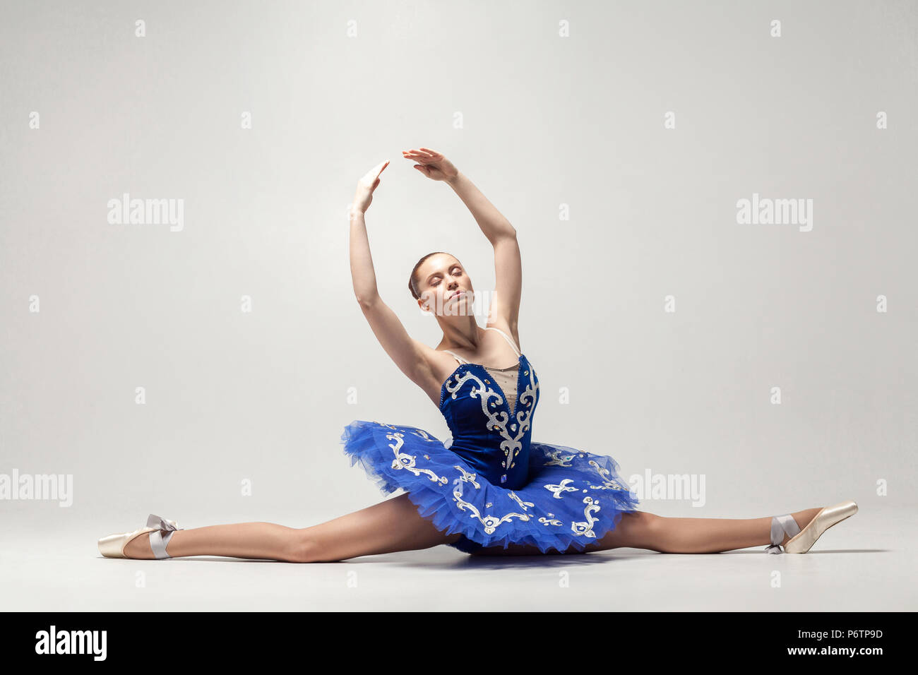 attractive ballerina with bun collected hair wearing blue dress and ...