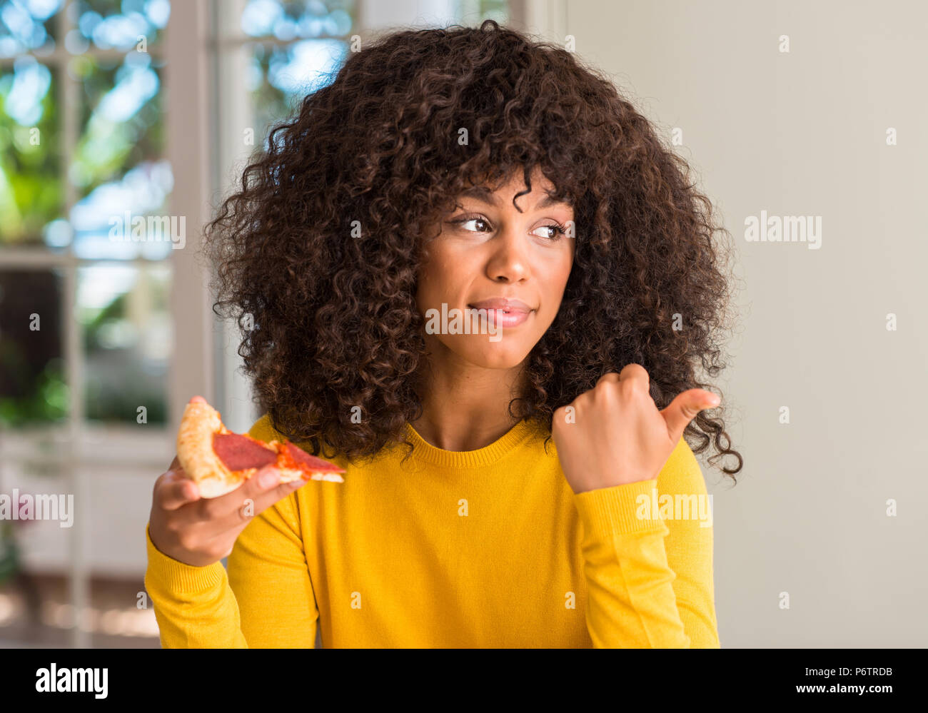 African american woman ready to eat pepperoni pizza slice pointing with ...