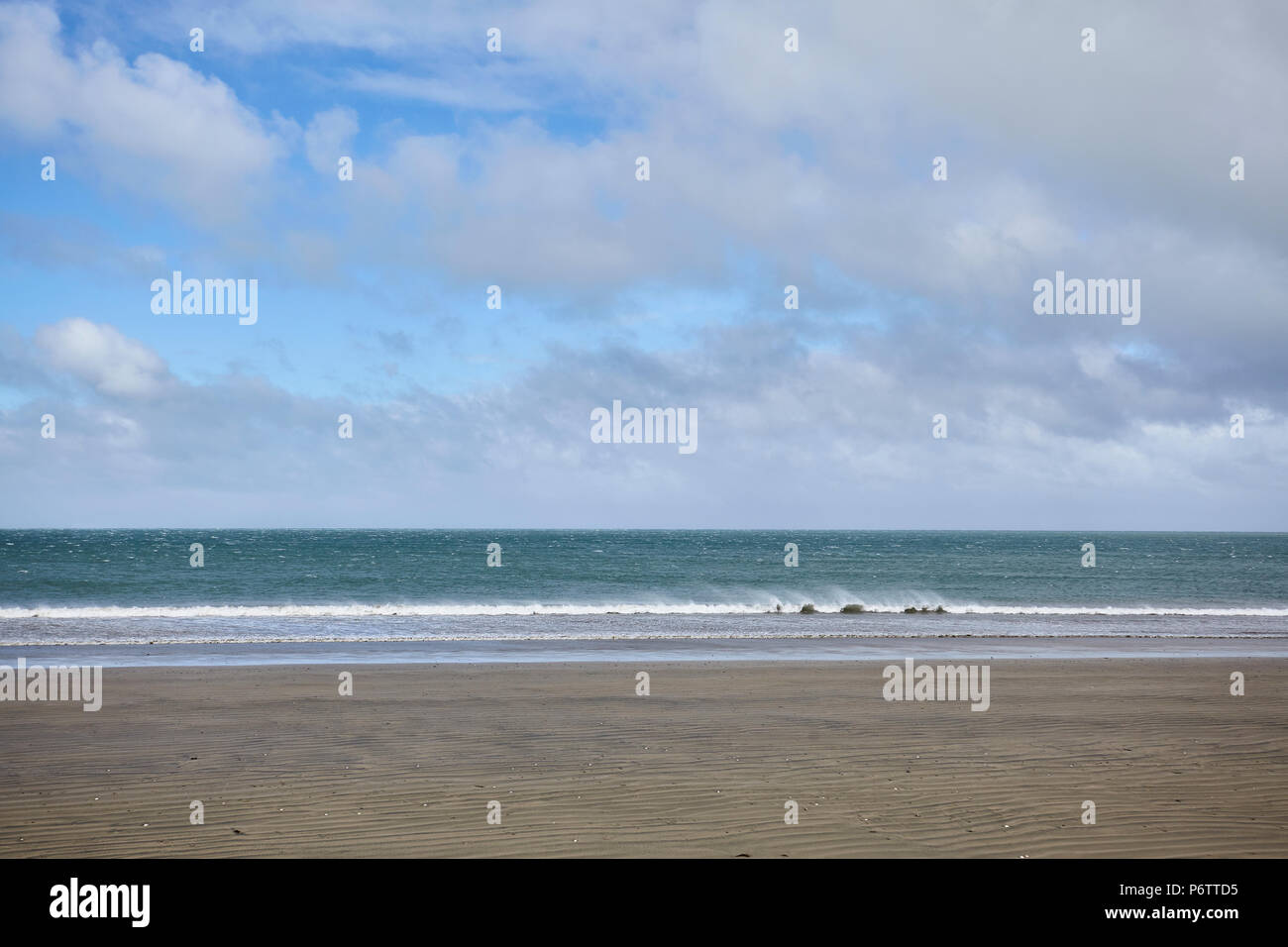 View from a beach on the west coast of New Zealand looking out to the Tazman Sea as a wave breaks on to the shore Stock Photo