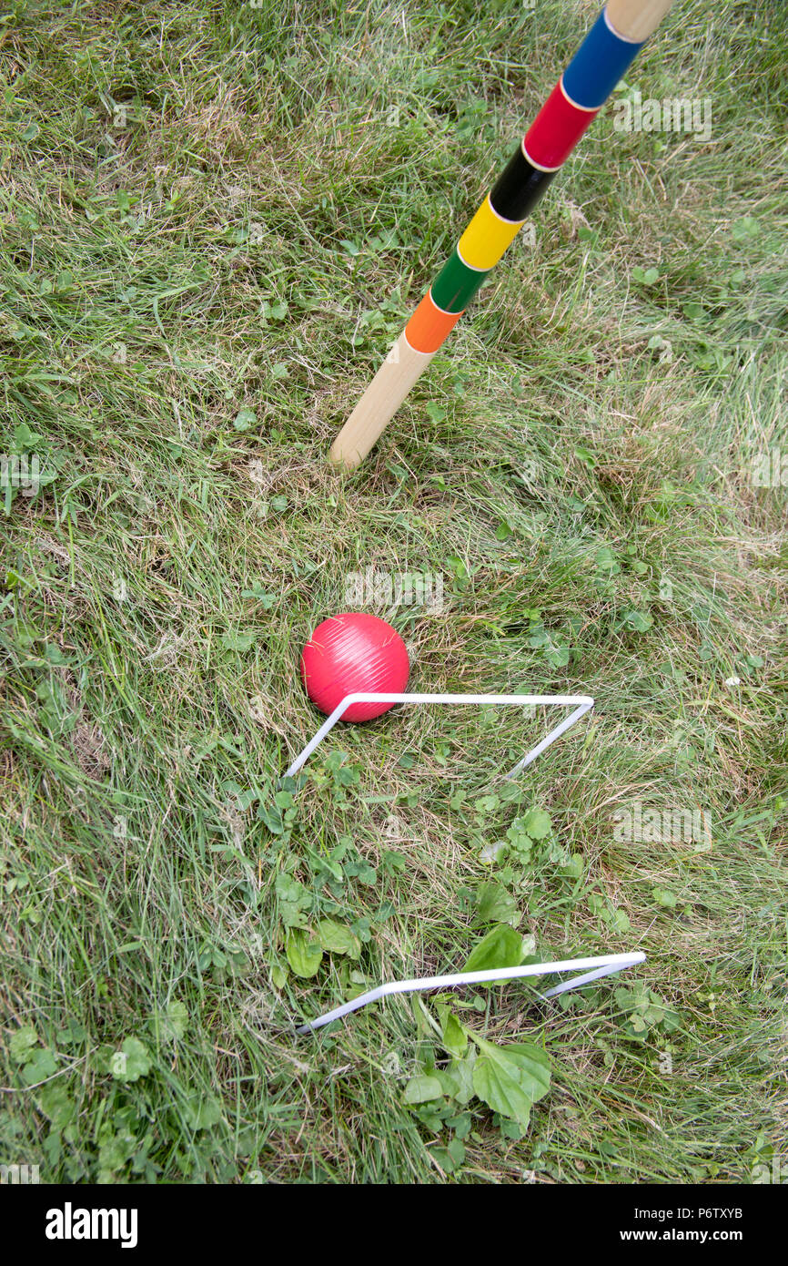 Outdoor croquet game set with pole, wickets and red ball in grassy park. Stock Photo