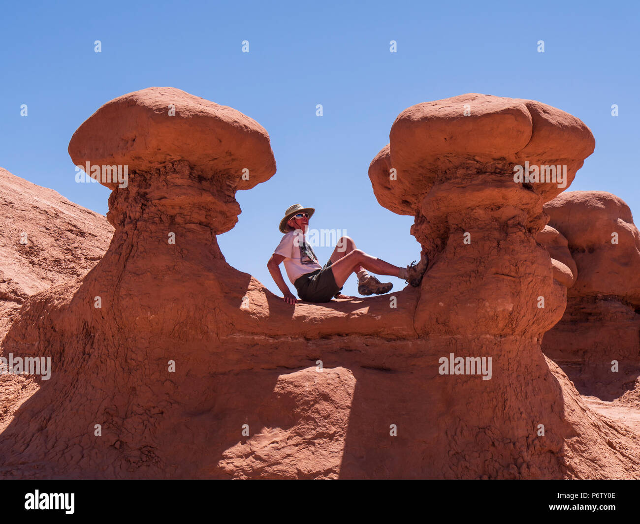 Woman sits between two goblins, Goblin Valley State Park, Hanksville, Utah. Stock Photo
