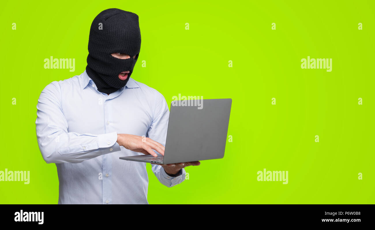 Business hacker man holding a computer laptop scared in shock with a surprise face, afraid and excited with fear expression Stock Photo