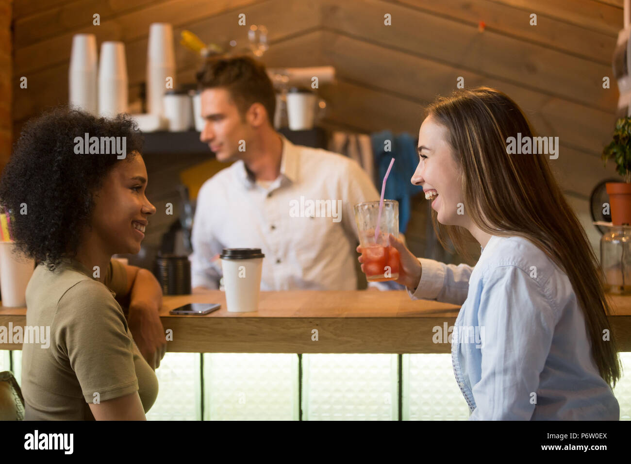 Multiracial girlfriends laughing, enjoying drinks at bar counter Stock Photo