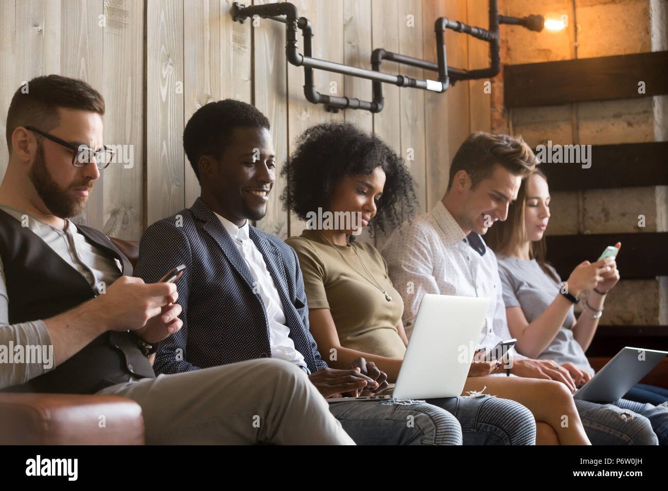 Multiracial millennials sit avoid talking using gadgets Stock Photo