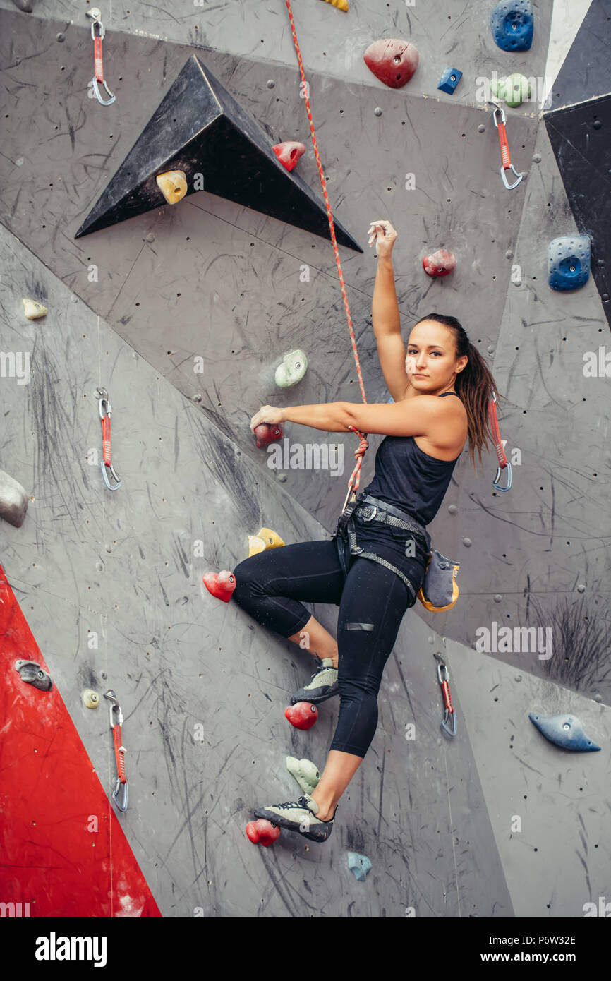 Beautiful young woman in black outfit looking at camera climbing