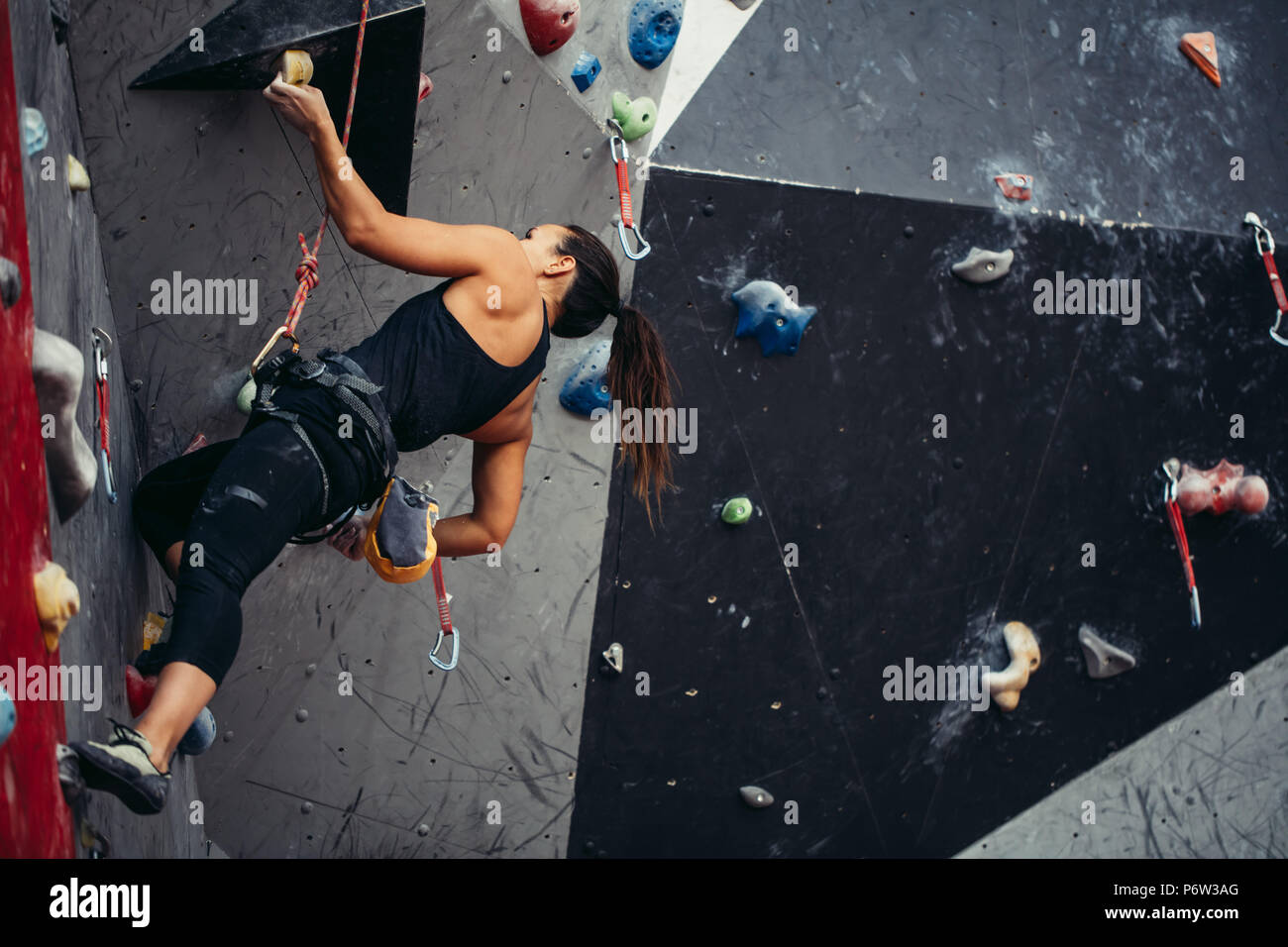 Professional climber woman in black outfit, reaching the top of