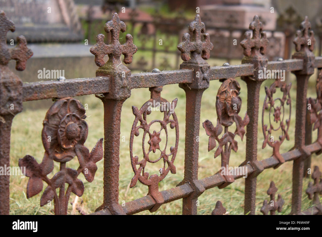 A rusted, decorated, wrought iron fence around a grave marker in Brompton Cemetary, London Stock Photo