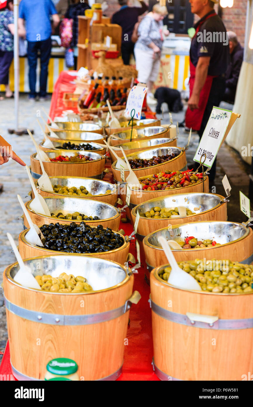 Different types of olives, stored in small open barrels, being sold on