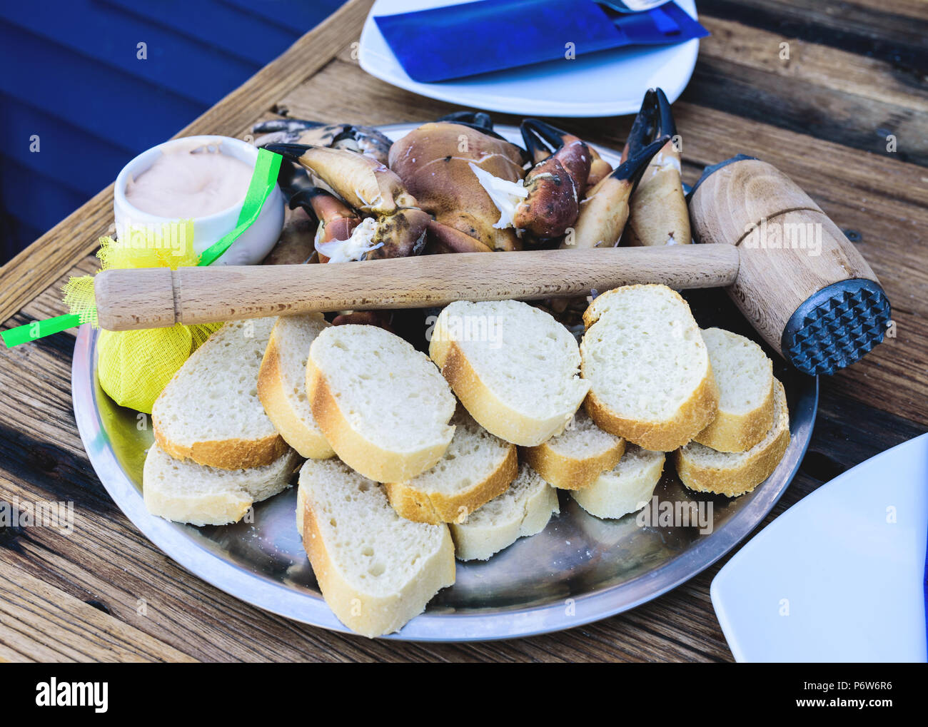 plate with boiled legs and claws of brown crab with bread and dip on wooden table Stock Photo