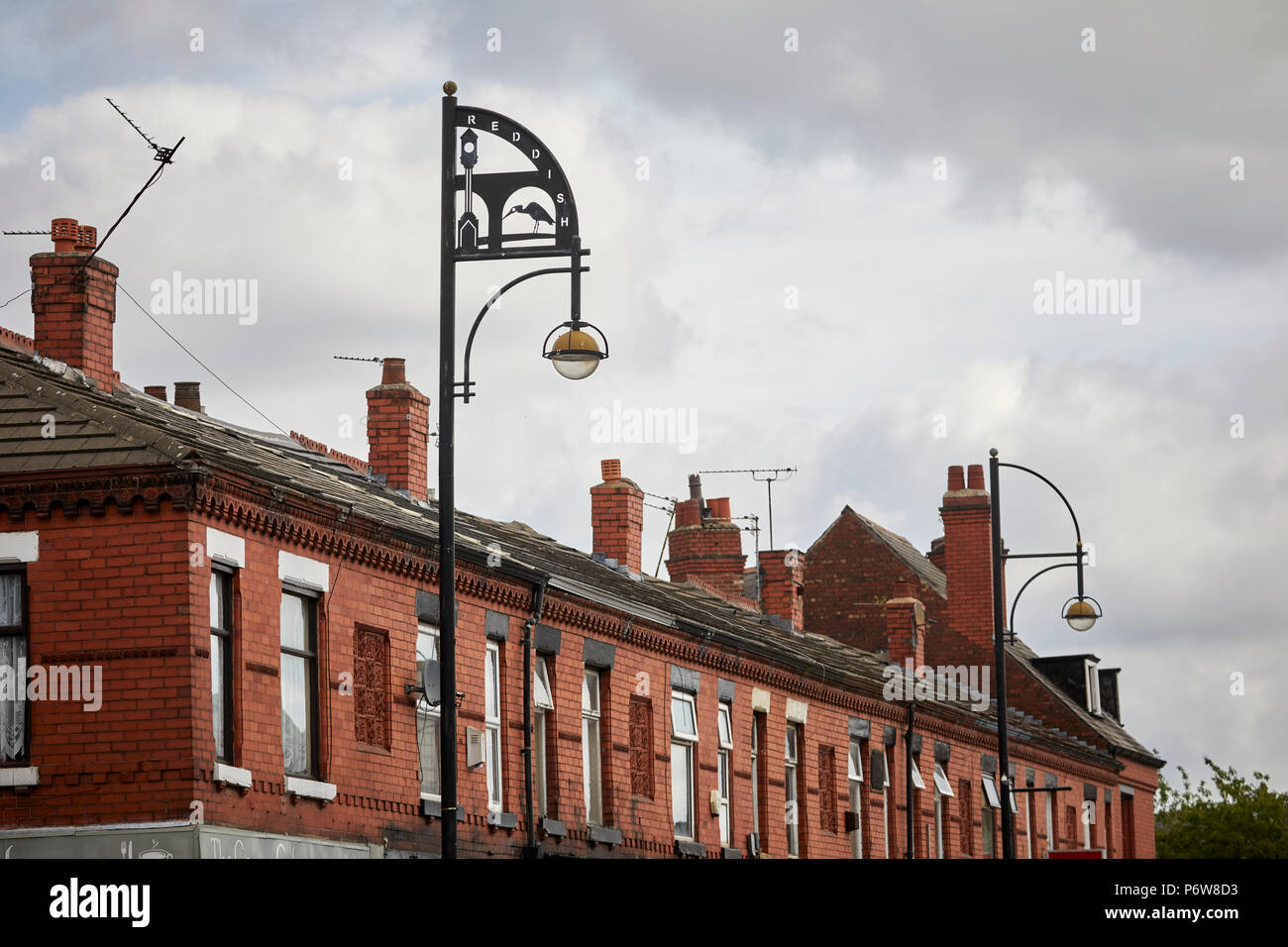 Reddish village shops in Stockport, Grater Manchester, Broadstone Road street light with reddish Vale and Houldsworth Square clock Stock Photo