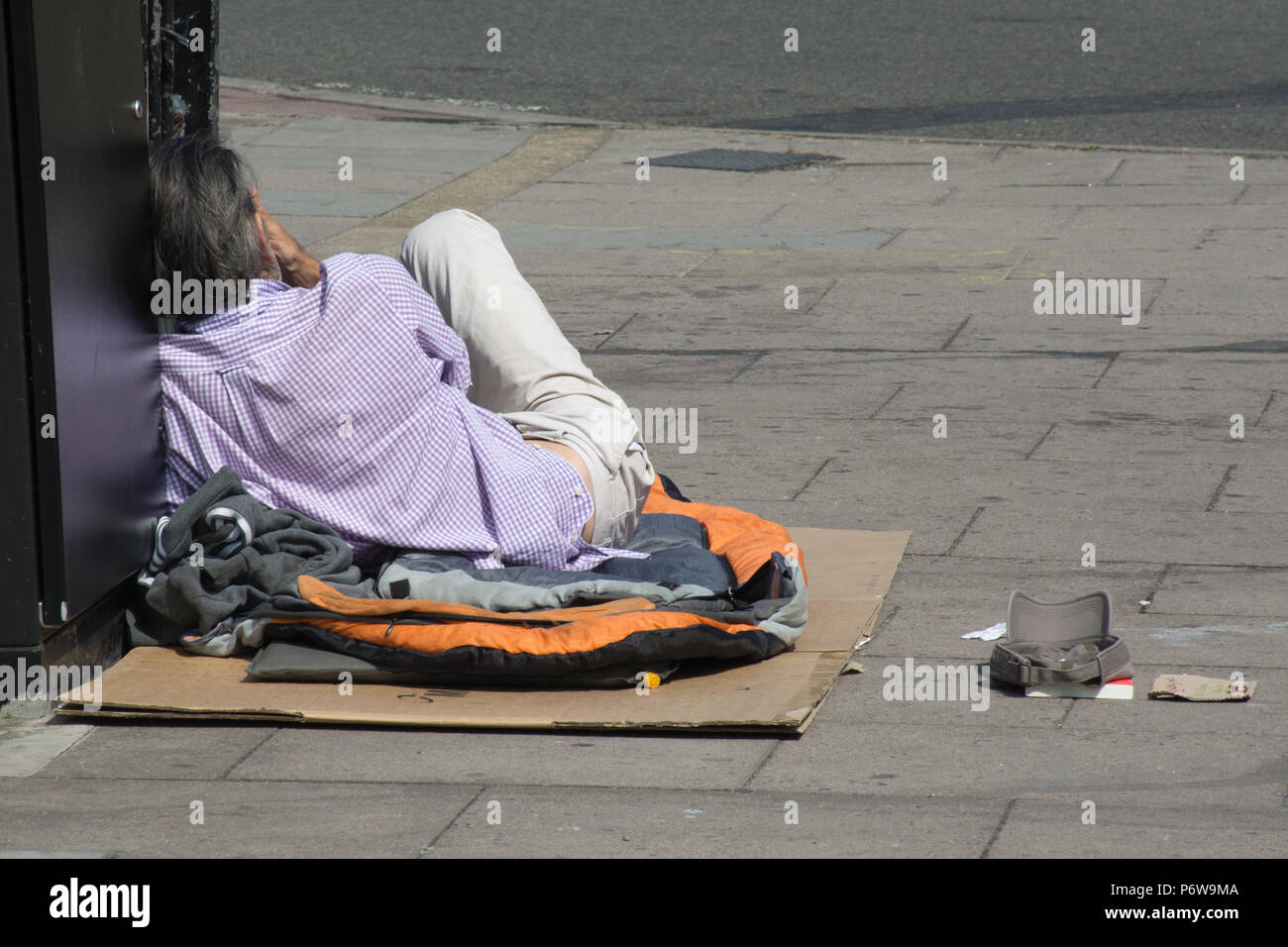 Homeless man on the pavement outside Guildford Railway Station in Surrey, UK Stock Photo