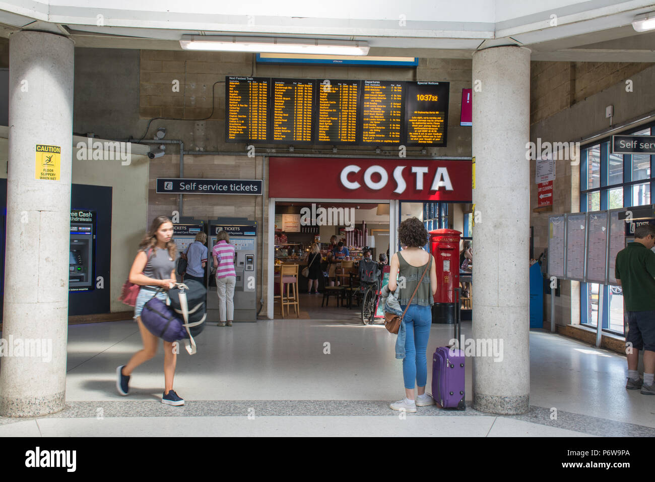 Inside the ticket office at Guildford railway station, with a Costa coffee shop and passengers buying tickets from self-service machines, Surrey, UK Stock Photo