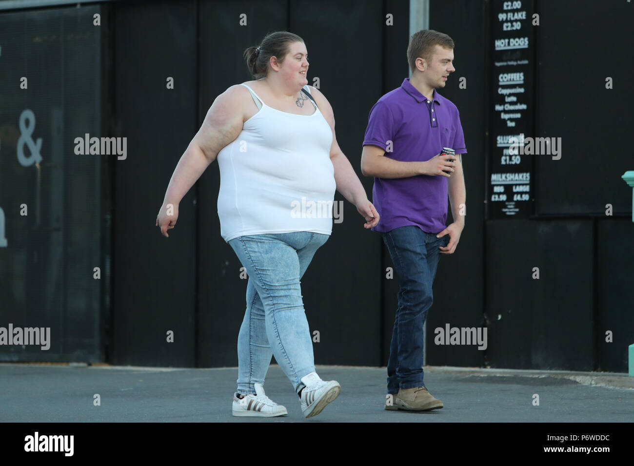 An overweight woman walking with a thin man Stock Photo