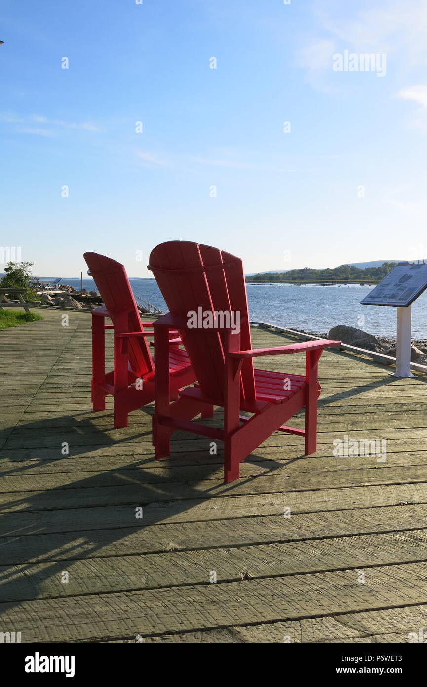 A Pair Of Bright Red Adirondack Chairs To Sit And Admire The View