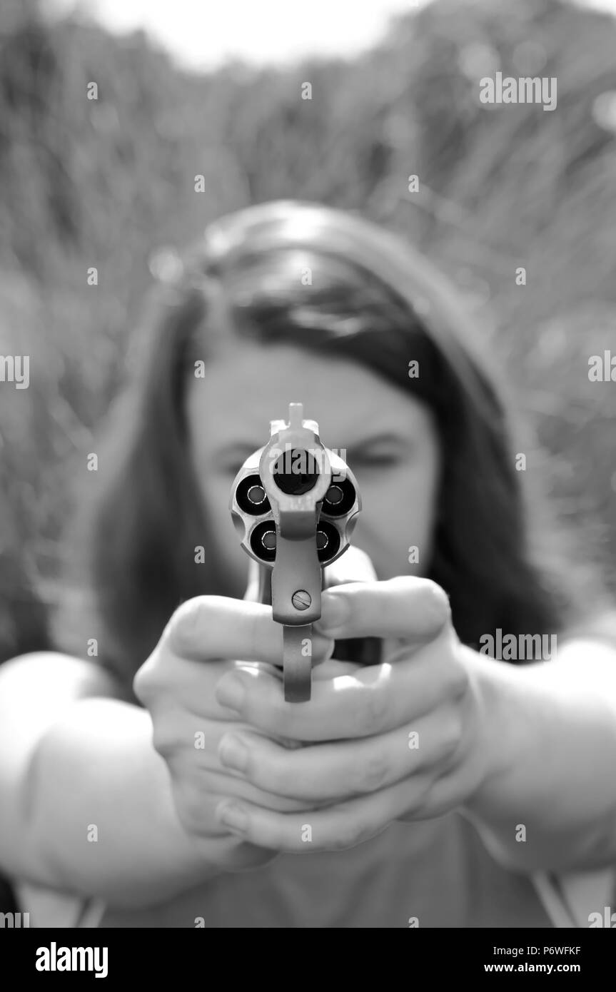 A girl aiming a revolver loaded with hollow point bullets shot in black and white Stock Photo