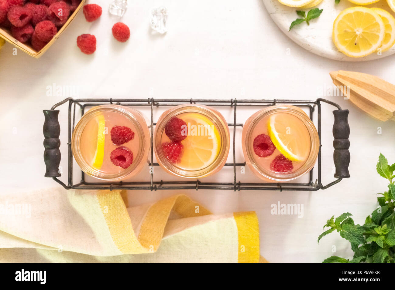 Raspberry lemonade in drinking mason jars on a white table. Stock Photo