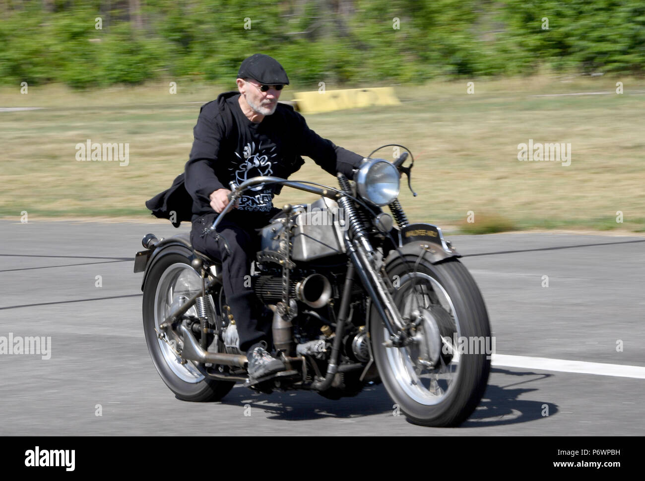 Hartenholm, Germany. 03rd July, 2018. Cartoonist Roetger Feldmann alias Broesel (L) driving to the press conference for the new edition of the legendary 'Werner' race on his self-built motorbike with a NSU engine. 30 years after the first 'Werner' race on the Hartenholm airfield, the competition between Holgi's Porsche and Broesel's 'Red Porsche Killer will be reissued from the 30 August 2018. Credit: Carsten Rehder/dpa/Alamy Live News Stock Photo