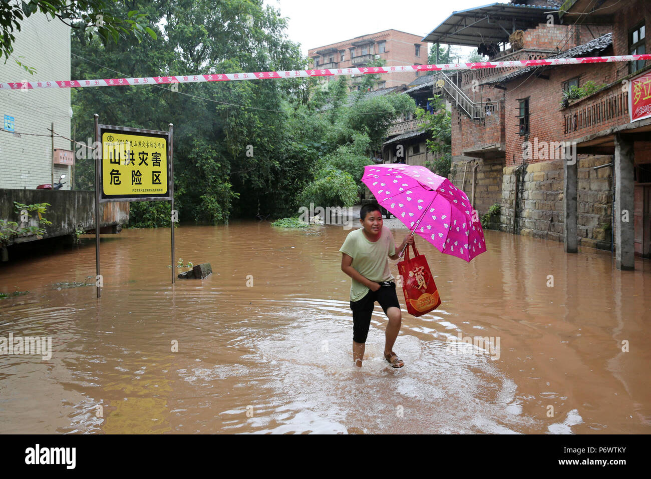 Neijiang, China's Sichuan Province. 3rd July, 2018. A resident wades in Tianjia Township of Neijiang, southwest China's Sichuan Province, July 3, 2018. Provincial flood control headquarters said a total of 115,900 people in Sichuan were affected by heavy rains. Crops, roads, bridges and school buildings were damaged. meteorological station said. Credit: Lan Zitao/Xinhua/Alamy Live News Stock Photo