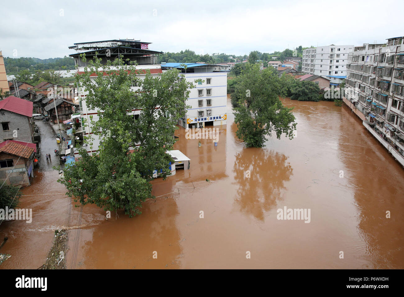 Neijiang. 3rd July, 2018. Photo taken on July 3, 2018 shows residential buildings in flood water in Tianjia Township of Neijiang, southwest China's Sichuan Province. Provincial flood control headquarters said a total of 115,900 people in Sichuan were affected by heavy rains. Crops, roads, bridges and school buildings were damaged. Credit: Lan Zitao/Xinhua/Alamy Live News Stock Photo