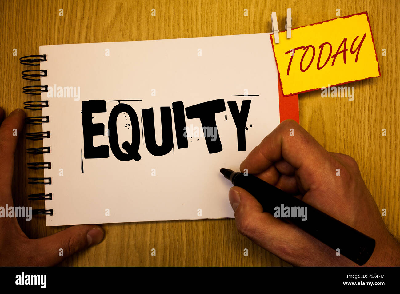 Handwriting text writing Equity. Concept meaning Value of a company divided into equal parts owned by shareholders Man hold holding black marker noteb Stock Photo