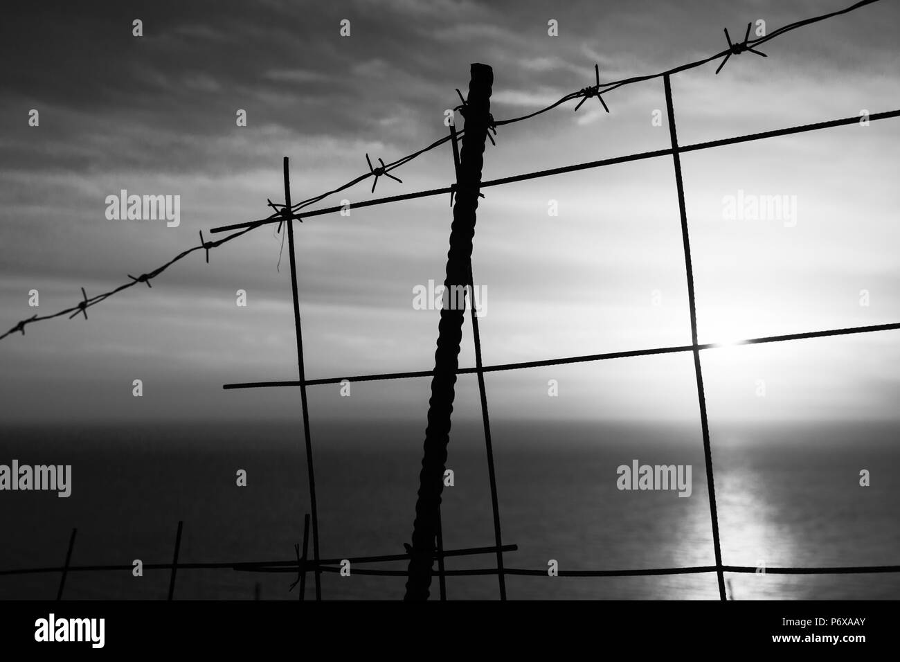 Barbed wire fence with sea on a background. Black and white landscape of Zakynthos Stock Photo