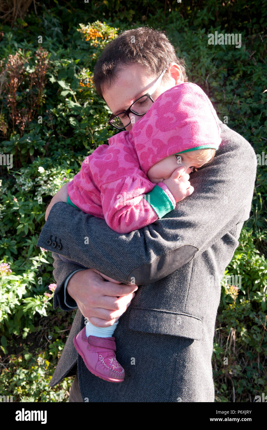 Baby girl sucking her thumb being held and comforted by her father Stock  Photo - Alamy