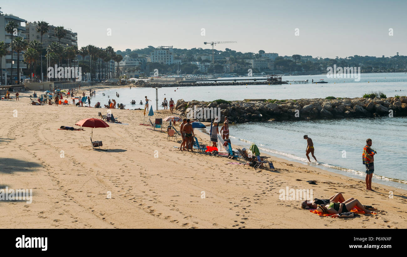 Early morning sun bathers and swimming at the Juan les Pins beach, a popular resort destination on the Mediterranean Stock Photo