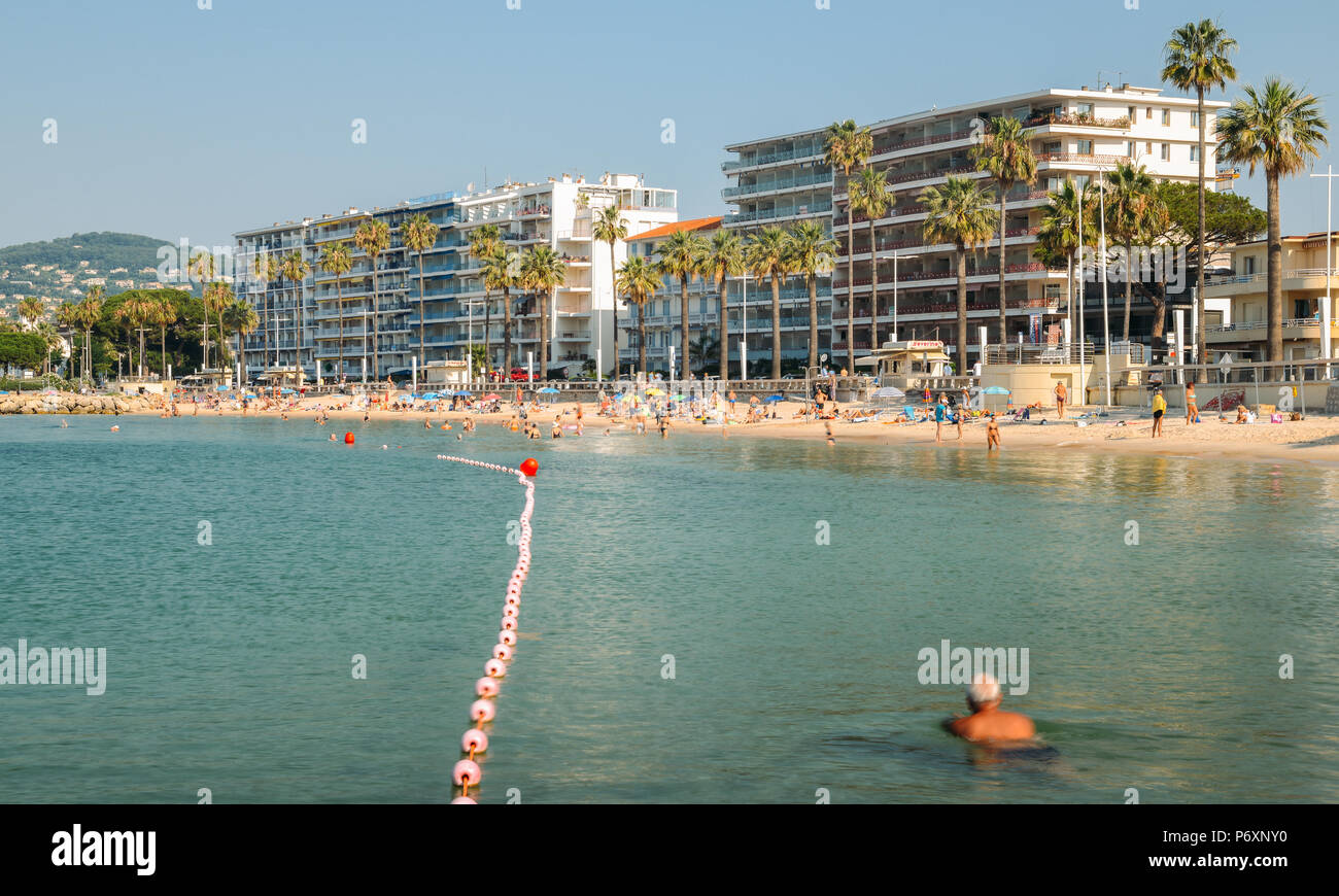 Early morning sun bathers and swimming at the Juan les Pins beach, a popular resort destination on the Mediterranean Stock Photo