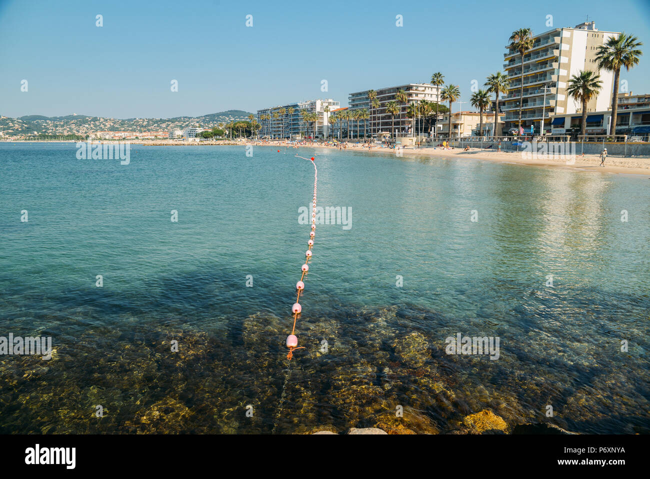 Early morning sun bathers and swimmers at the Juan les Pins beach, a popular resort destination on the Mediterranean Stock Photo