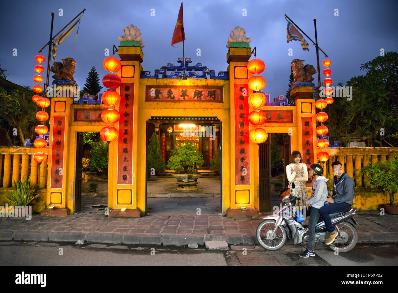 Guys on Motorbike in frong of Minh Huong, communal house of Hoi An  Hoi An , Vietnam Stock Photo