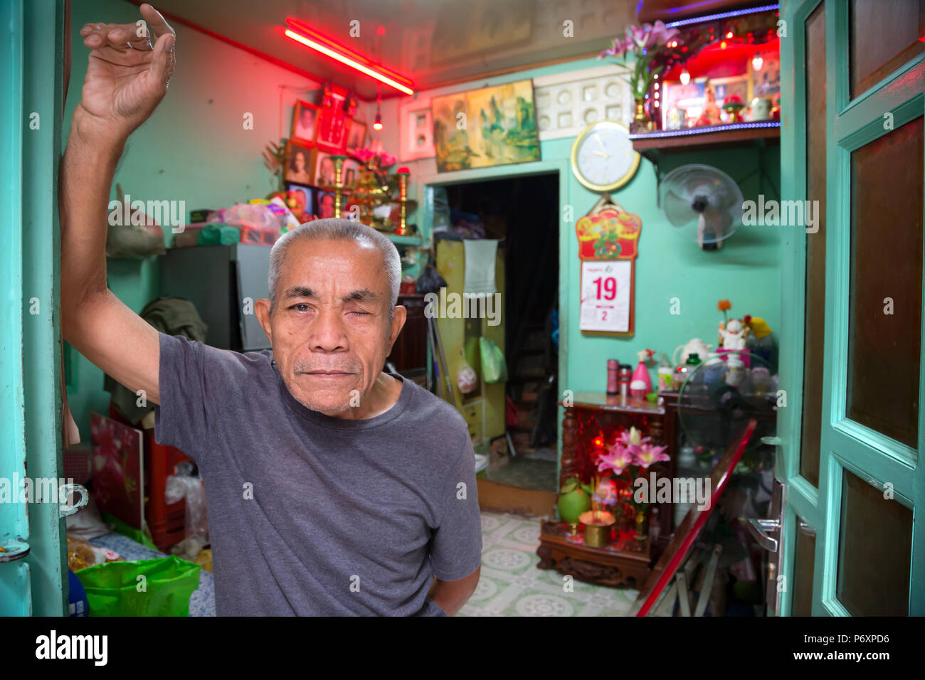 Man stands at the entrance of his house in old area of Saigon, Vietnam Stock Photo