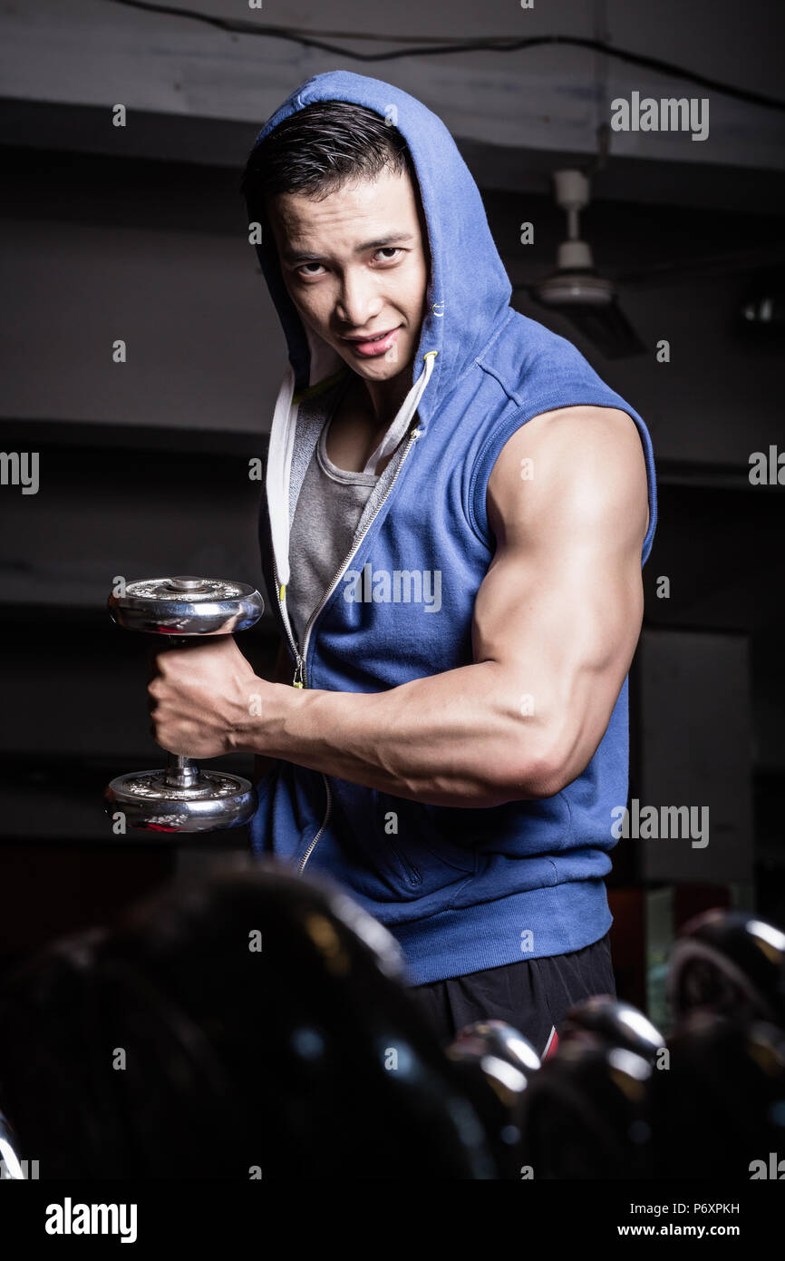 Young man reaching out with dumbbell in his hand Stock Photo