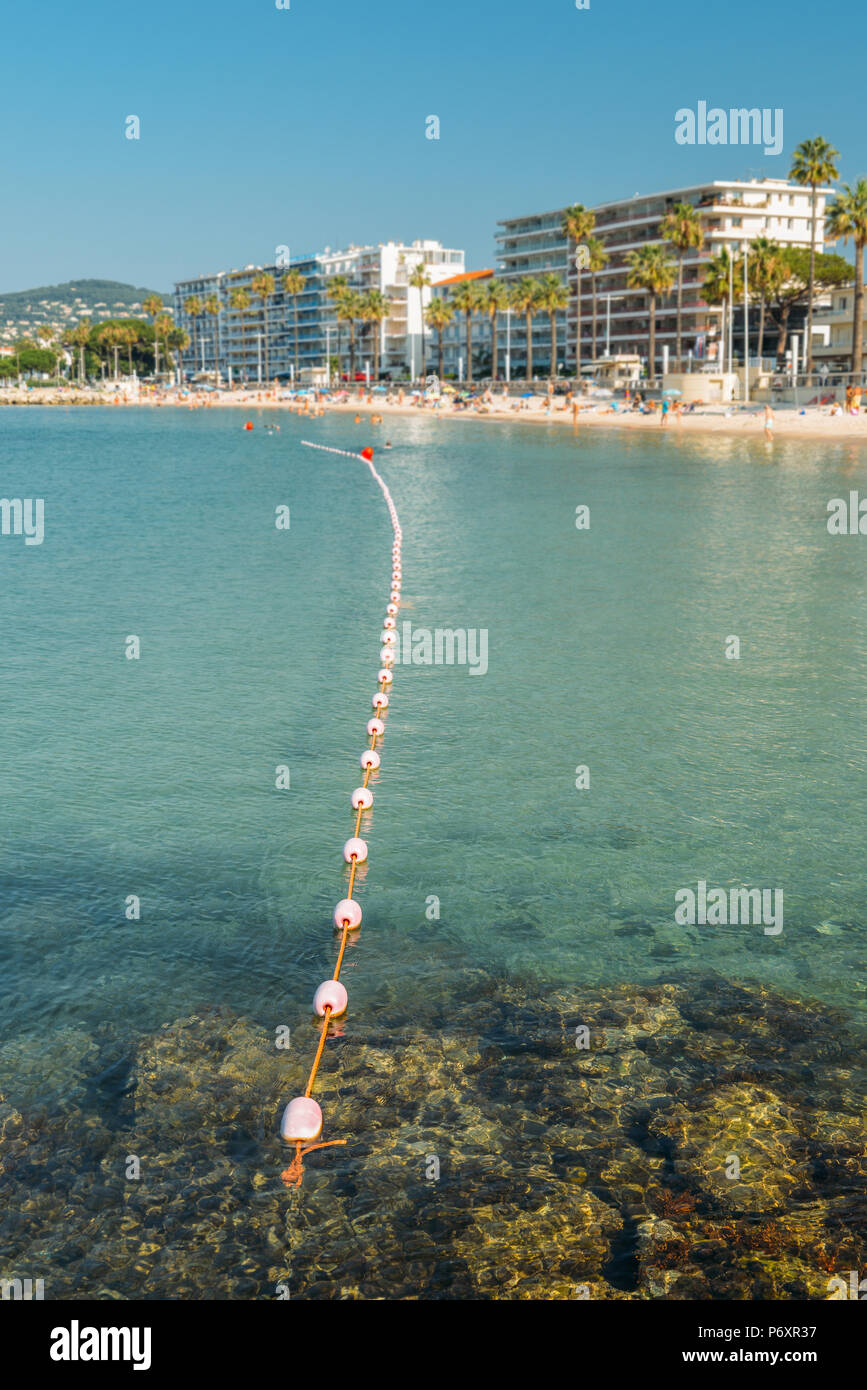 Early morning unidentifiable sun bathers and swimming at the Juan les Pins beach, a popular resort destination on the Mediterranean Stock Photo