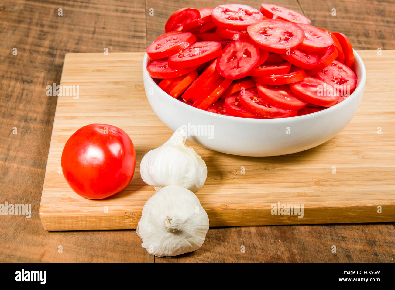 Garlic cloves and bowl of red sliced tomatoes Stock Photo - Alamy