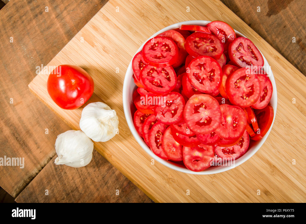 Garlic cloves and bowl of red sliced tomatoes Stock Photo - Alamy