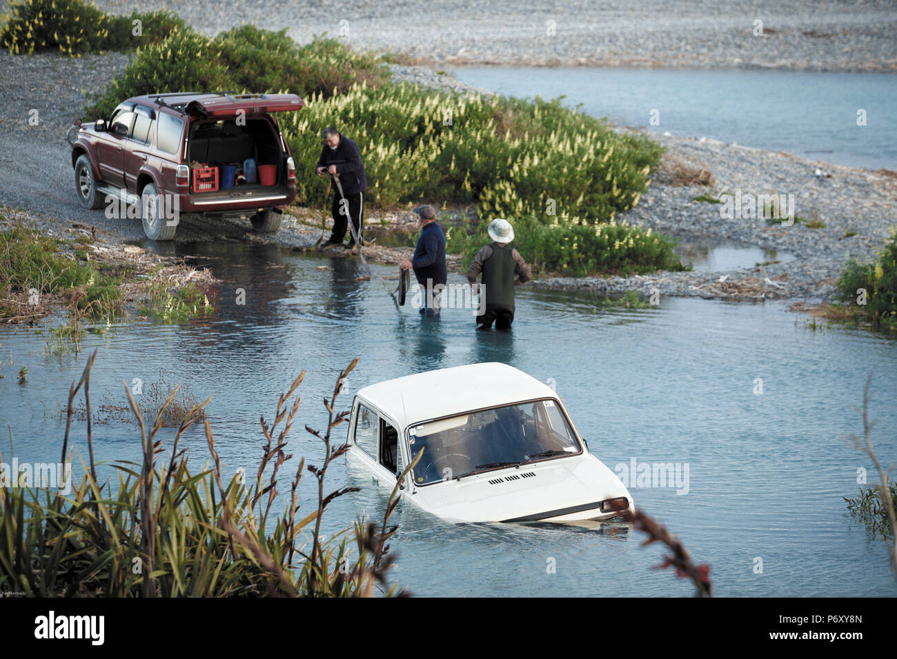Men tow out Lada four wheel drive vehicle stuck in coastal lagoon Stock