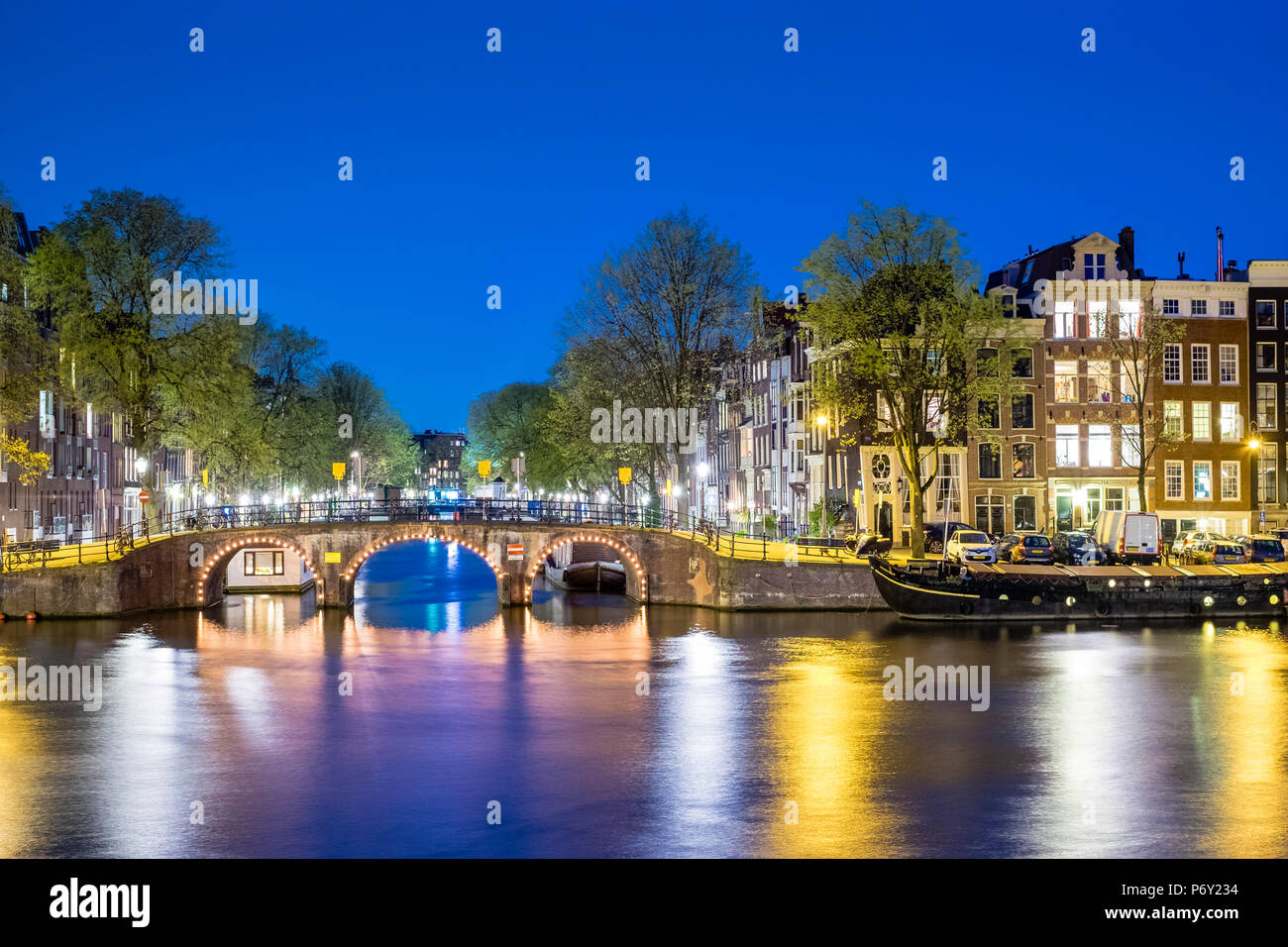Netherlands, North Holland, Amsterdam. Canal houses along the Amstel River at night. Stock Photo