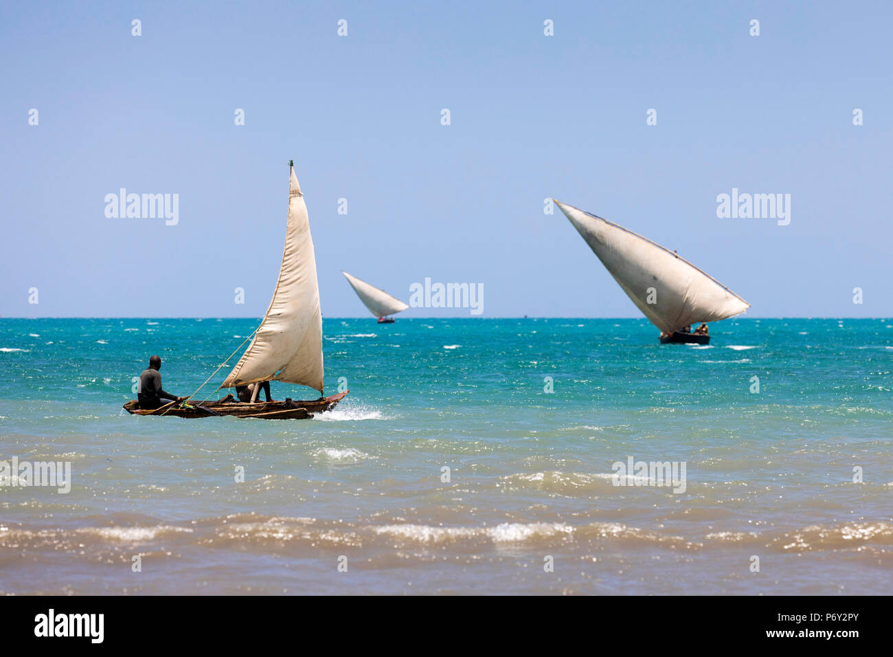 Three small dhows are out fishing near the coast, Zanzibar, Tanzania Stock Photo