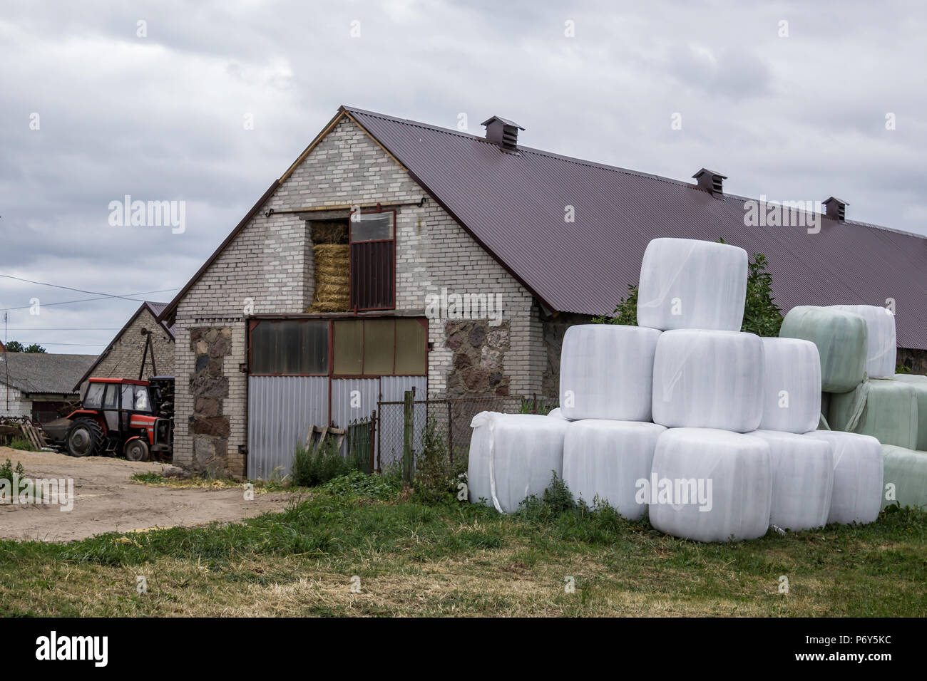 Stacked like a pyramid,bales of silage, wrapped in a membrane.Food for the cows in the winter, near the barn for the cows.Farm in Podlasie, Poland. Stock Photo