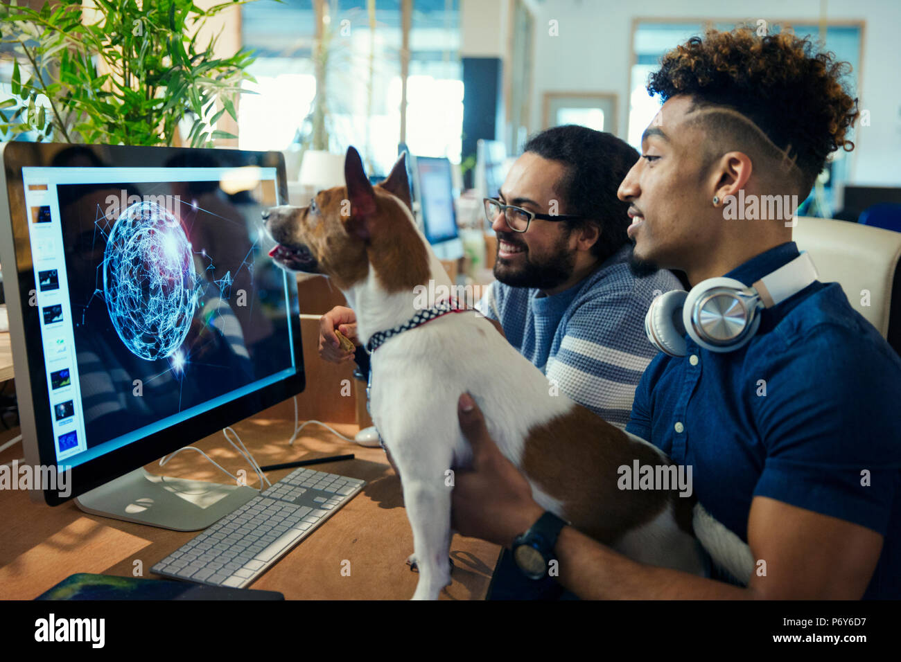 Graphic designers with dog working at computer in office Stock Photo