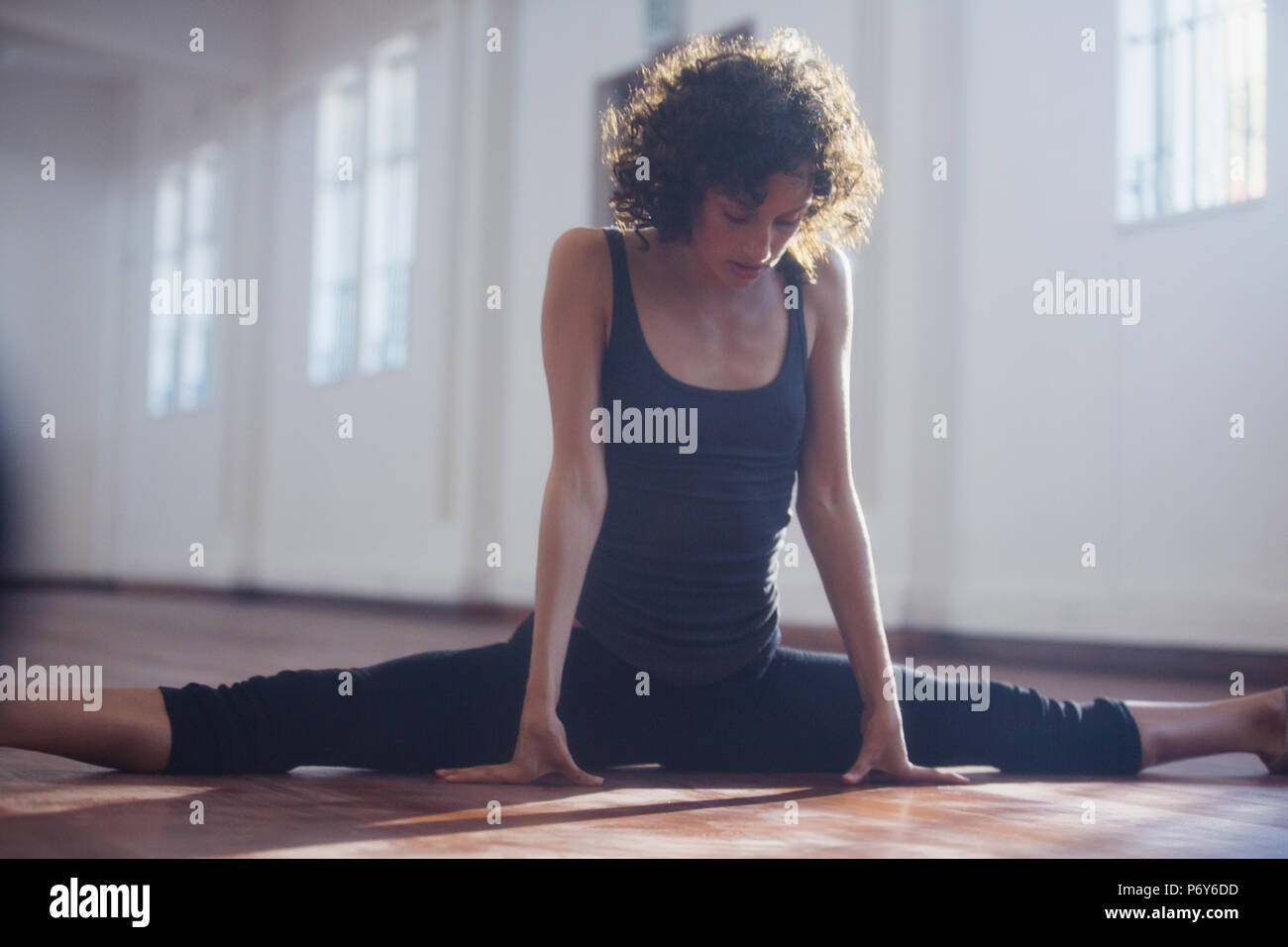 Strong young female dancer stretching, doing the splits in dance studio Stock Photo